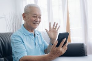 elderly-man-making-video-call-and-waving-at-screen